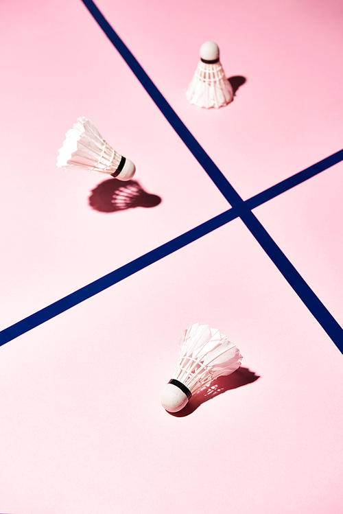 High angle view of badminton shuttlecocks on pink surface with blue lines
