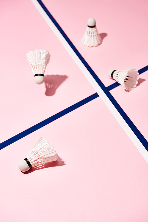 Badminton shuttlecocks with shadow on pink surface with blue lines