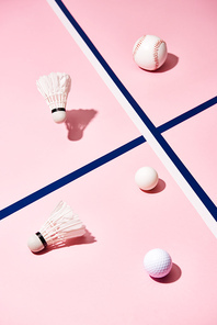 Badminton shuttlecocks with tennis, baseball and golf balls on pink surface