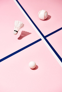 Balls for tennis, baseball and badminton shuttlecocks on pink surface with blue lines