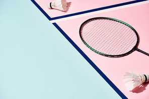Badminton racket and shuttlecocks on colorful surface with blue lines