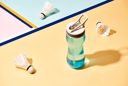 Water bottle and badminton shuttlecocks on surface with colorful lines