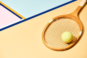 Yellow tennis ball on wooden racket on background with blue lines