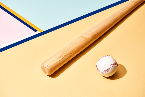 Wooden baseball bat and ball on colorful background with lines