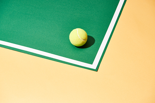 Tennis ball with shadow on green and yellow surface with white line