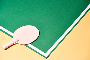 Table tennis racket on playing table on yellow surface