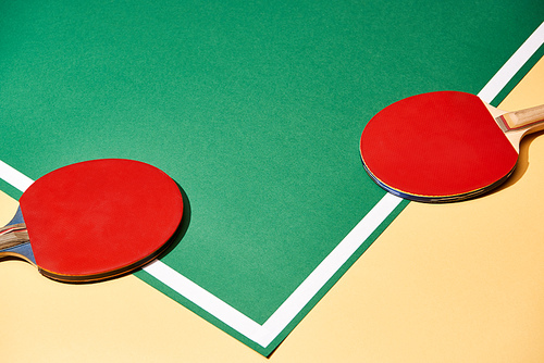 Two ping pong rackets on yellow and green surface