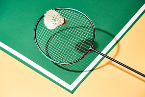Badminton racket and shuttlecock on green and yellow surface with line