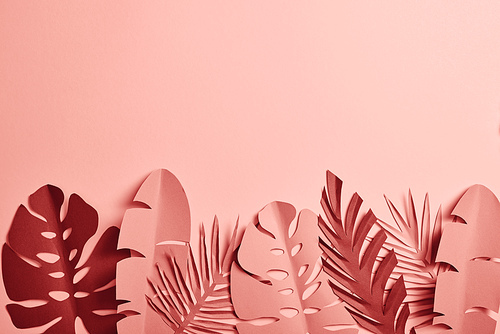 top view of paper cut palm leaves on pink background