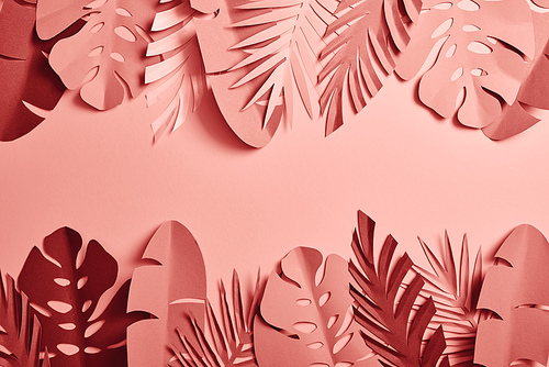 top view of paper cut palm leaves on pink background with copy space