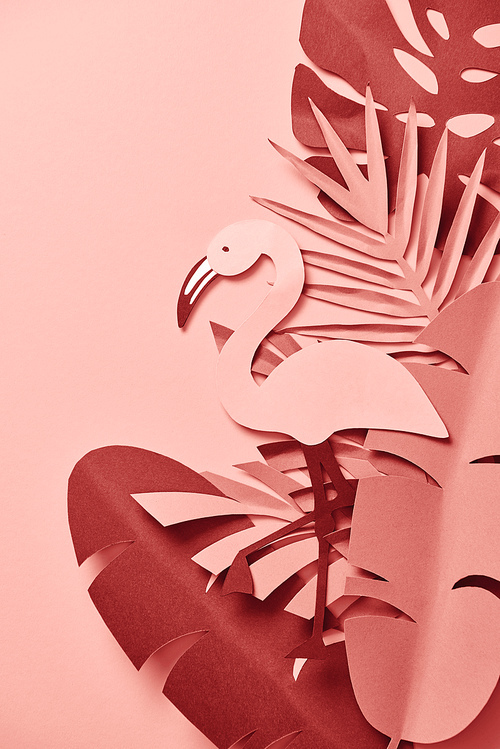 top view of paper cut flamingo among palm leaves on pink background