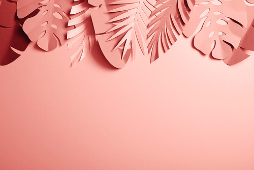 top view of exotic paper cut palm leaves on pink background