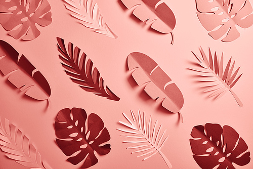 top view of paper cut palm leaves on pink background, seamless pattern