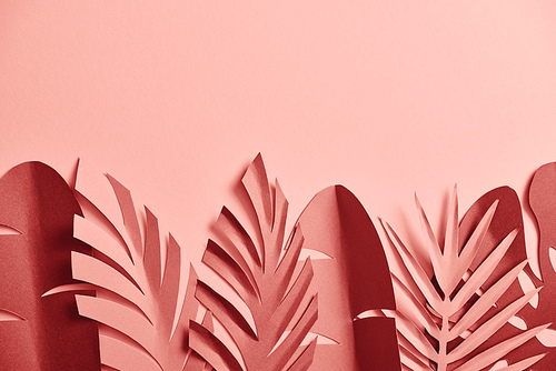 top view of decorative paper cut palm leaves on pink background with copy space