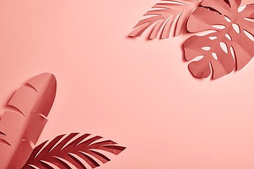 top view of paper cut exotic leaves on pink background with copy space
