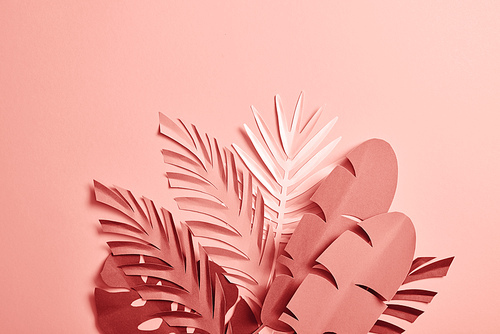 bunch of paper cut palm leaves on pink background