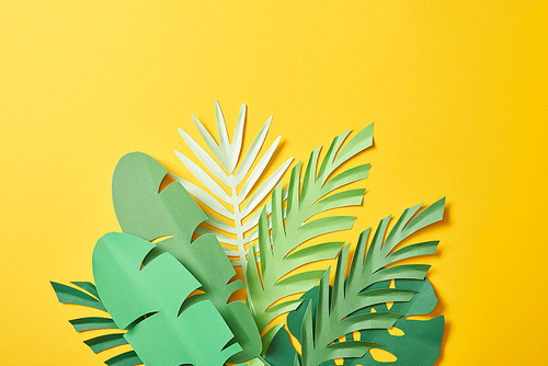 bunch of paper cut exotic green palm leaves on yellow background with copy space