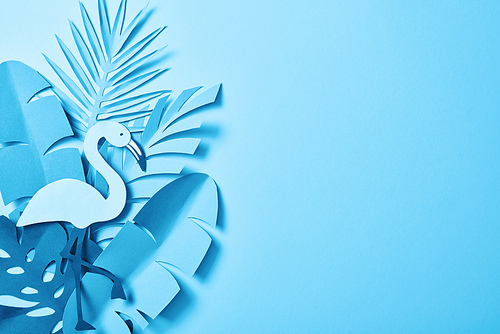 top view of blue minimalistic paper cut palm leaves on blue background with copy space