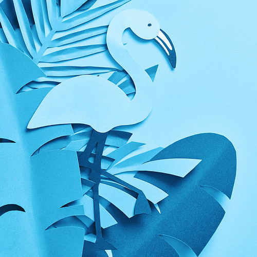 top view of blue paper cut palm leaves and flamingo on blue background