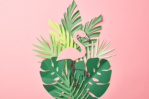 top view of paper cut flamingos on green palm leaves on pink background