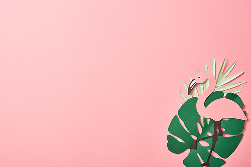 top view of paper cut flamingos on green palm leaves on pink background with copy space