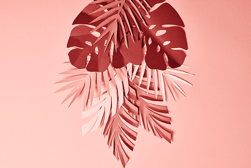 top view of paper cut palm leaves on pink background