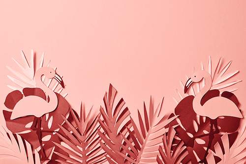 top view of paper cut colorful palm leaves and flamingos on pink background