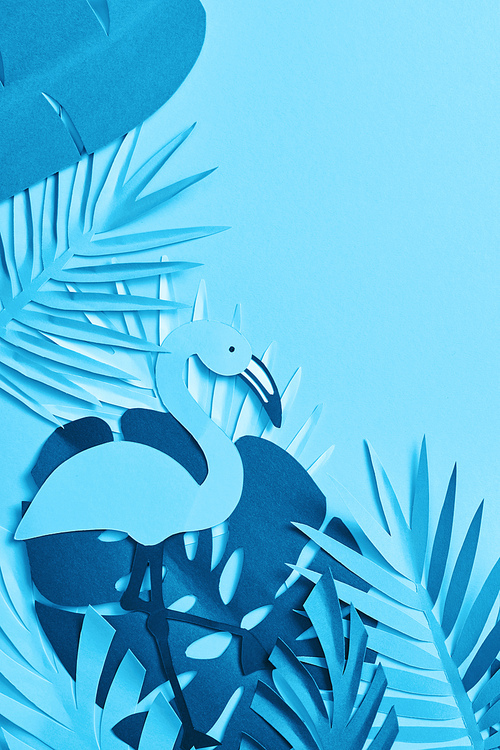 top view of blue minimalistic paper cut palm leaves and flamingo on blue background with copy space