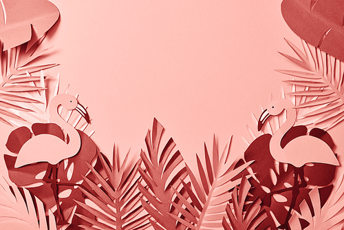 top view of pink exotic paper cut palm leaves and flamingos on pink background with copy space