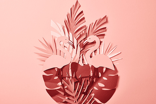 top view of pink exotic paper cut palm leaves and flamingos on pink background