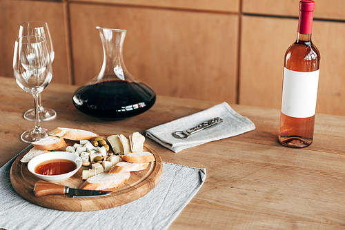 bottle of wine, jug, wine glasses and food on wooden table