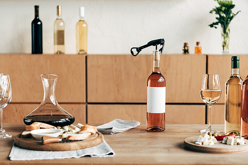 bottles of wine, wine glasses, jug and food on wooden table
