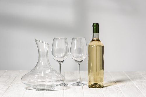 empty wine glasses, bottle of wine and jug on wooden surface in restaurant