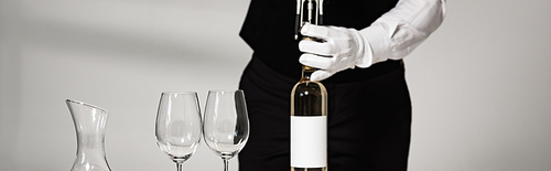 panoramic shot of waiter in white glove opening bottle of wine in restaurant