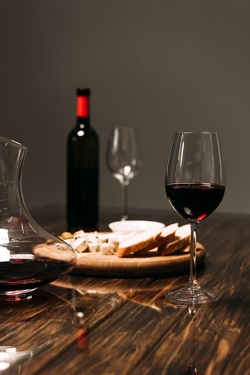 wine glasses, jug, bottle of wine and food on wooden table in restaurant