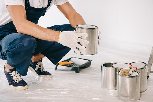 cropped view of painter in uniform holding can with paint