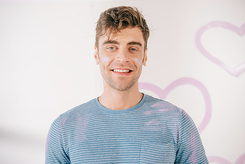 handsome young man with stains of pink paint on face 