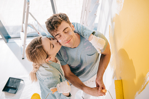 high angle view of girl kissing boyfriend painting wall in yellow