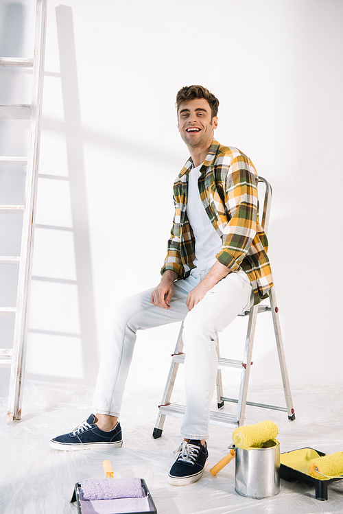 handsome young man smiling while sitting on ladder and 