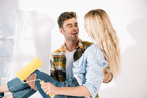 happy young man holding on hands girlfriend with yellow paint roller