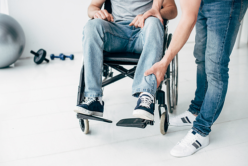 Cropped viw of Physiotherapist massaging leg of patient in wheelchair in hospital