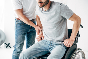 Physiotherapist helping handicapped man in Wheelchair during recovery