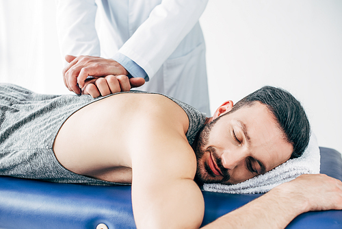 chiropractor massaging back of man lying on Massage Table in hospital