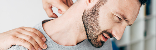 panoramic shot of chiropractor massaging neck of man