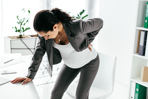 pregnant woman leaning on table because of pain