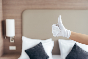 partial view of maid in white glove showing thumb up in hotel room