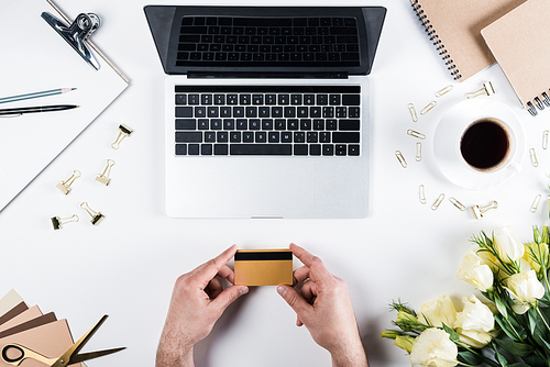 partial view of man holding credit card at workplace