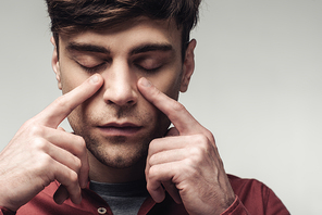 blind man pointing at closed eyes isolated on grey, human emotion and expression concept