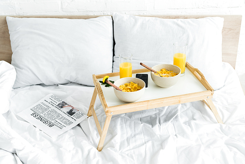 high angle view of tray table with breakfast on white bed in bright room