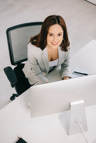 high angle view of young, smiling secretary  while sitting at workplace